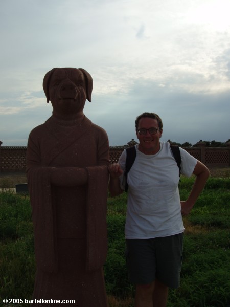 Author poses beside a pig sculpture at Astana Tombs near Turpan, Xinjiang, China