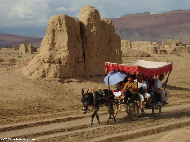 Donkey cart carries tourists through Gaochang Ruins near Turpan, Xinjiang, China
