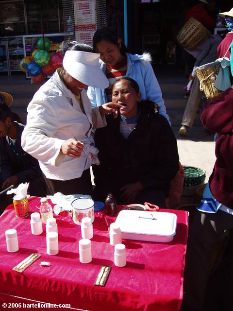 Dental work being performed on the street at the Youshuo market in Yunnan province, China